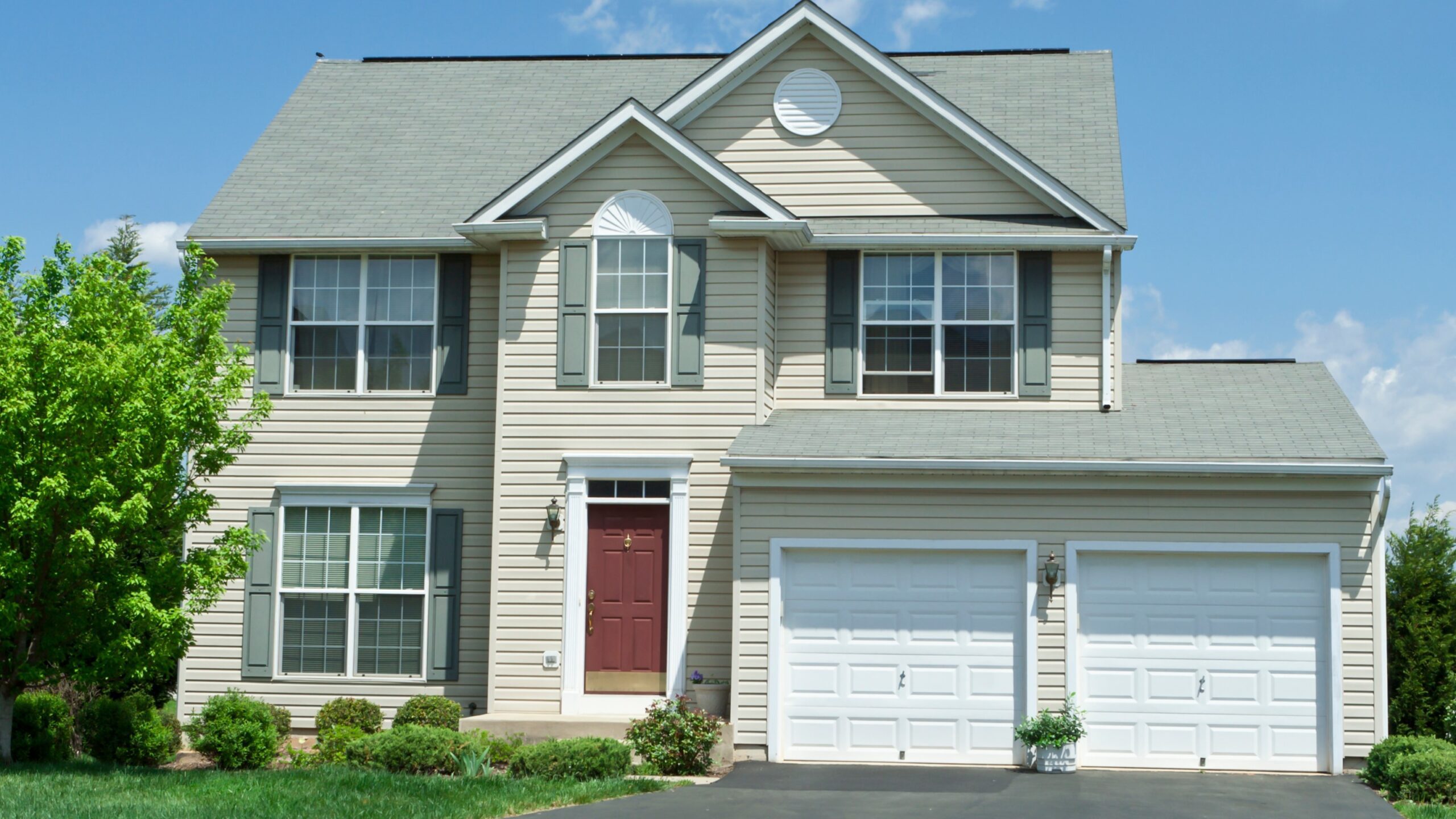 Large home with white vinyl siding, white garage doors, and beautiful new replacement windows
